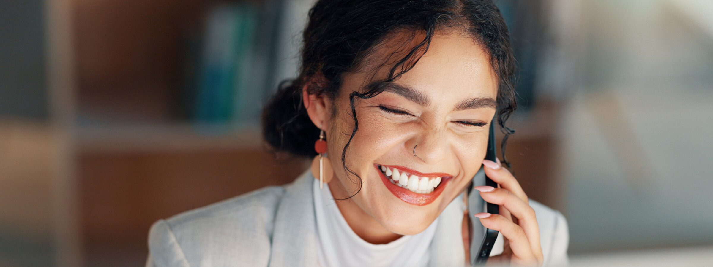 Nahaufnahme einer Frau, die herzlich lächelnd am Telefon spricht. Sie wirkt glücklich und entspannt, während sie mit jemandem telefoniert.