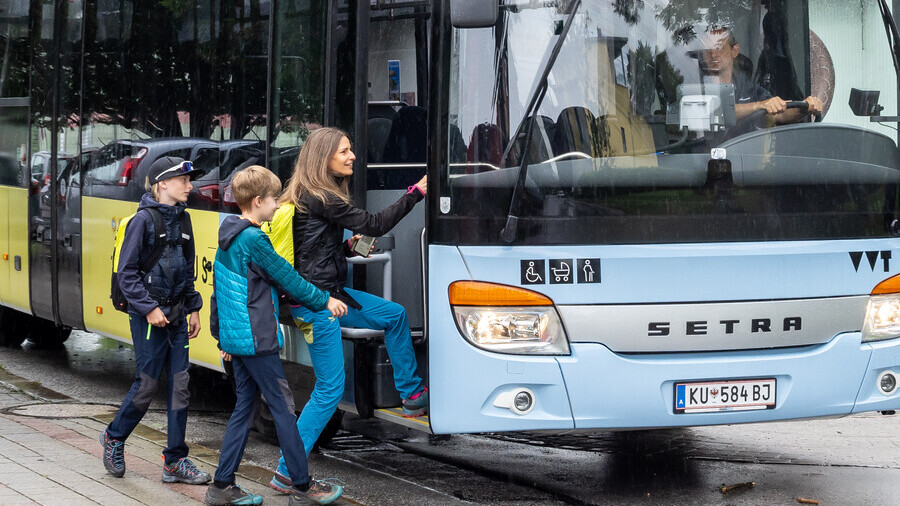 Drei Personen steigen in den Bus ein.