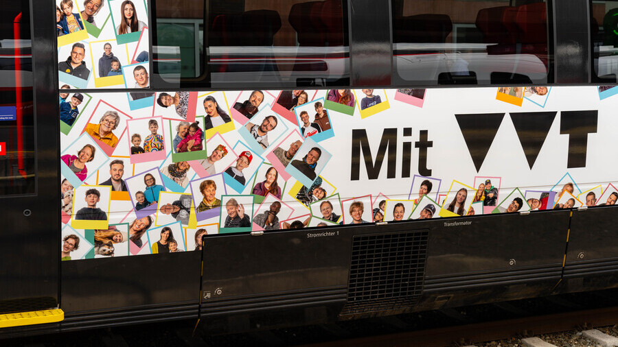 Am Bild ist ein Ausschnitt des Jubiläumszugs zu sehen mit lauter bunten Kacheln und darin Porträts von Öffi Fans. Außerdem der steht der Schriftzug 'Mit VVT'. 